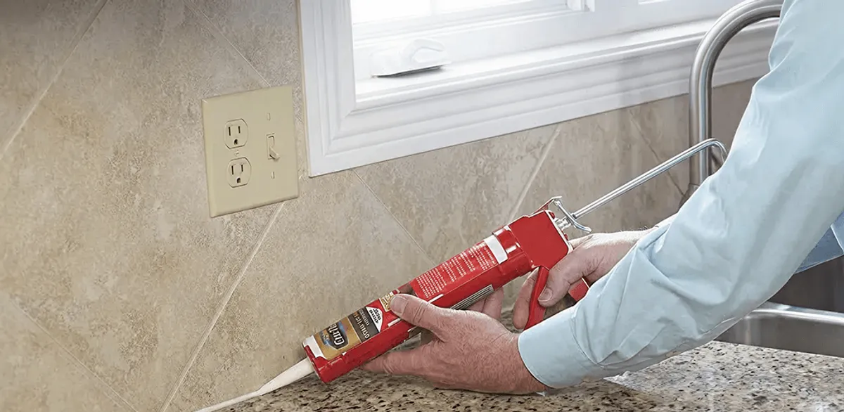 Handyman applying caulk along a kitchen backsplash and countertop seam in Salt Lake City, UT