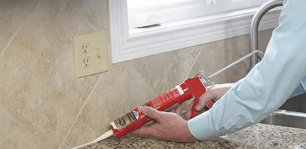 Handyman applying caulk along a kitchen backsplash and countertop seam in Salt Lake City, UT
