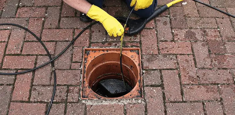 Drain cleaning technician using a drain snake to clear a clogged drain in Salt Lake City, UT
