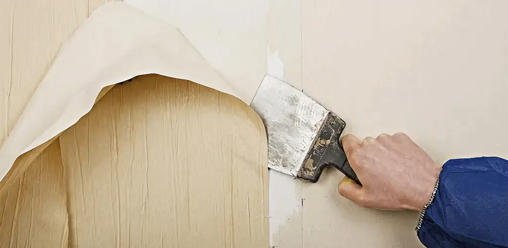 Handyman removing wallpaper with a scraper for wall preparation in Salt Lake City, UT
