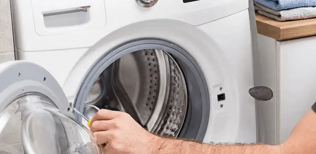 Handyman repairing a front-load washing machine and inspecting the drum in Salt Lake City, UT