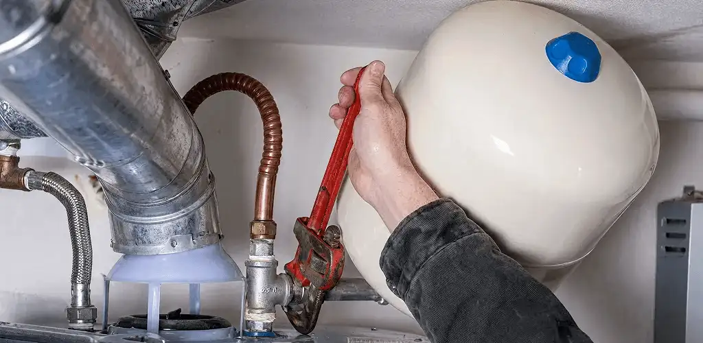 Water heater repair technician tightening plumbing connections near a tank unit in Salt Lake City, UT